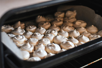 Trey with freshly baked sweet merengues in the oven.Cooking merengues at home. Selective focus. Low DOF