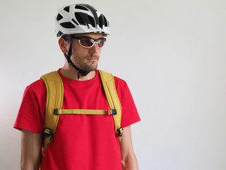Portrait of bicycle courier, with yellow backpack. Man in helmet and glasses. White background..