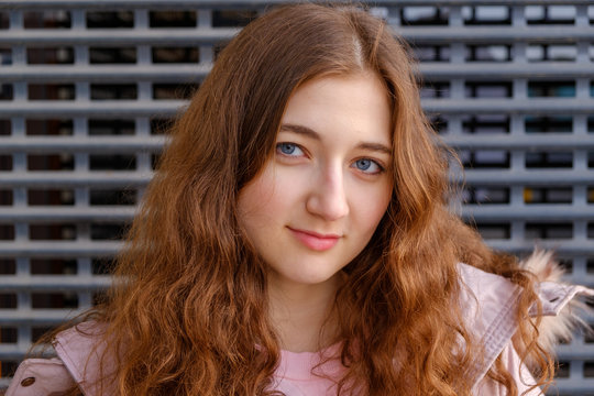The red-haired girl looks straight into the camera with a slight sneering smile while her long red hair is strewn over her shoulders