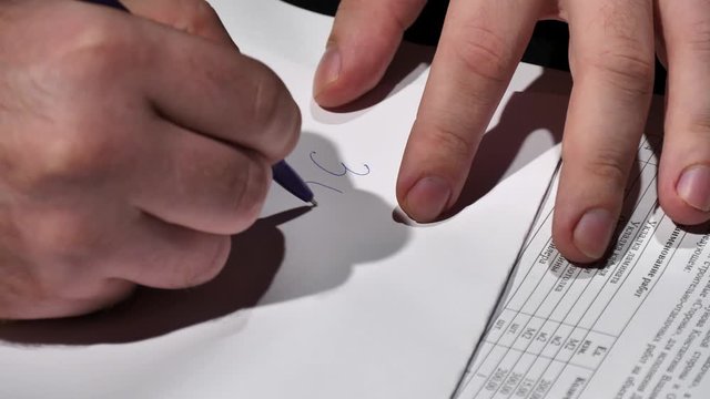 An official writes the amount of a bribe on a white sheet.