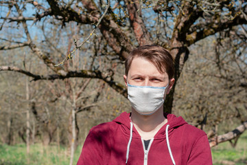 the man is in wild garden. reusable gauze mask on the face to protect against coronavirus. pandemic time. protection against viruses, coronavirus transmitted by airborne droplets.