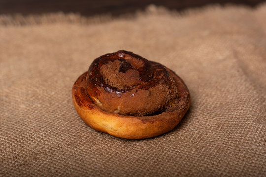 a baked cinnamon roll lies on a linen napkin on the table. homemade baking