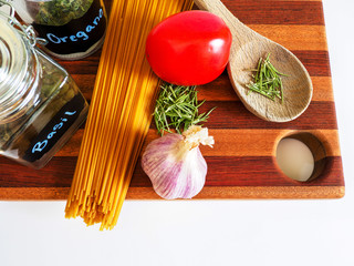 italian pasta recipe ingredients of spaghetti rosemary tomato and garlic with wooden spoon
