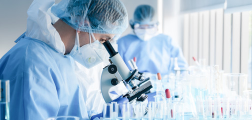 biochemical research scientist team working with microscope for coronavirus vaccine development in...