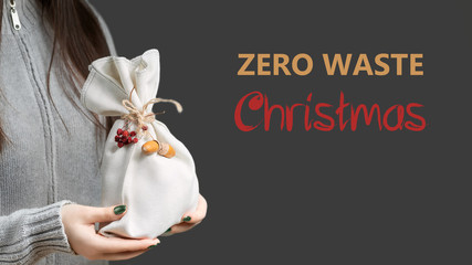 Zero waste and eco friendly christmas concept. Young woman holding in her hands wrapped in natural fabric. Lettering Zero Waste Christmas