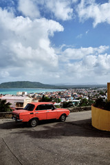 Baracoa, Cuba - aerial view of the town and the sea with a classic car in foreground