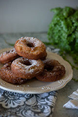 Doughnuts and a cup of tea or coffee with green plants and white linen