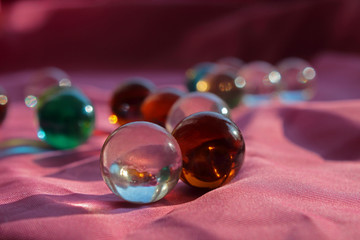 multi-colored glass balls on a pink cloth