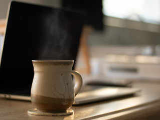 Working from Home with cozy cup of coffee and laptop on dining room table with technology including iPhone.