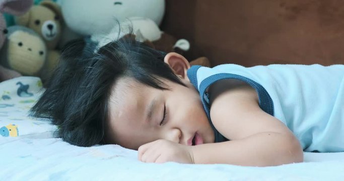 Cute Asian Baby Boy Lying On A White Bed With Monkey Dool