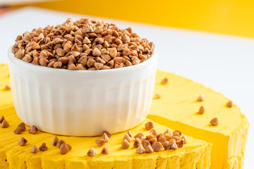 buckwheat in a white plate on a yellow wooden saw