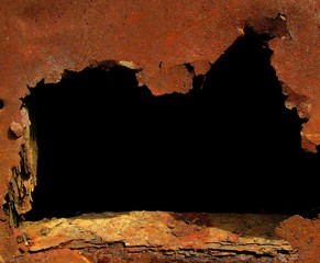A dark hole in a rusty wall