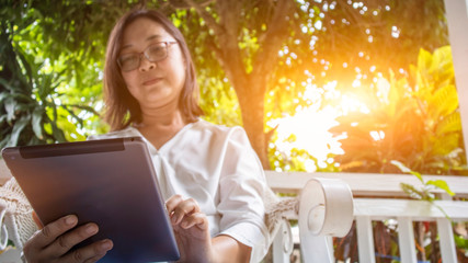 Asian woman check the purchase amount online from the tablet  in front of the house in the morning....
