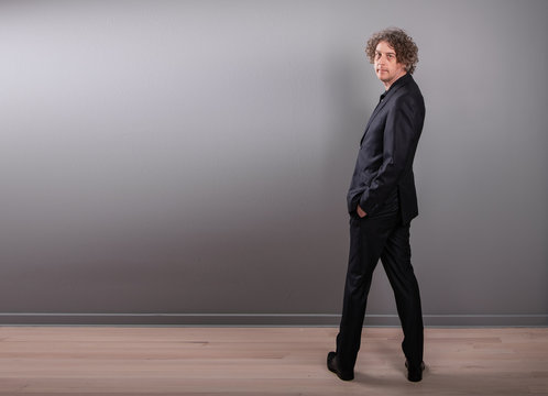 Studio portrait of a man wearing a business suit from behind. He turns torward the camera.