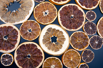Dried slices of various citrus fruits on dark blue background