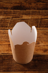 Big brown paper container isolated on wooden background. Eco-friendly disposable food packaging. Preserving nature and recycling concept.Copy space.