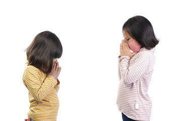 Social distance concept. Two little adorable Asian kids wearing a self-protect mask standing distance at 1meter and Greet with respect instead of hands touch (say hi to namaste) for safety.