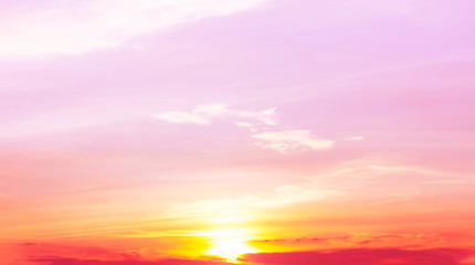sunset with orange and yellow light in pink sky and soft clouds