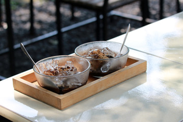 Traditional east Asian iced grass jelly dessert served in glass bowls on a table top outdoors in sunlight