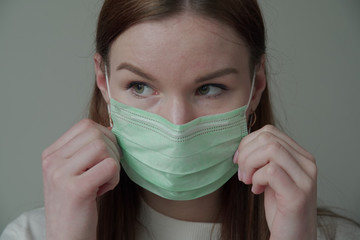 Close up of a beautiful young girl with long red hair in a medical mask. Orvi, coronovirus, acute respiratory infections.