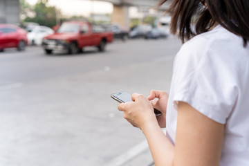 Asian tourist using taxi application on smartphone to make appointment with taxi driver. Woman searching for taxi driver by using smartphone. Modern urban transportation concept with copyspace.