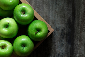 Green apples in a basket on a wooden background