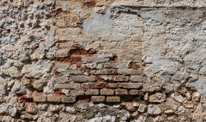 Stone and brick wall covered with lime. Old and rustic texture.