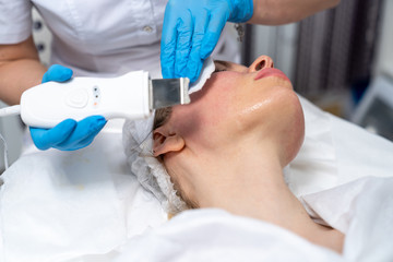 Obraz premium Beautician does facial skin cleansing for his client. Cleansing the skin with special tools. Facial cleansing mask.