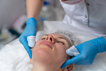 Beautician does facial skin cleansing for his client. Cleansing the skin with special tools. Facial cleansing mask.