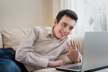 Young man lying on sofat and using laptop at home