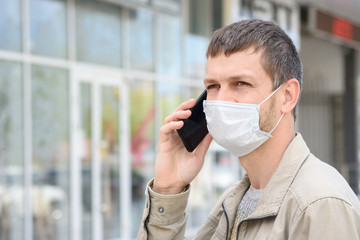 Portrait of a masked man with a mobile phone in the background of the store