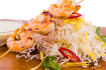 Shrimp skewers in coconut curry and Asian sauce on a wooden board