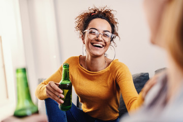 Young attractive smiling caucasian tanned woman with curly hair sitting with her best female...