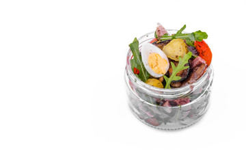 Salad with tufts of beef, eggplant and grilled tomatoes, arugula and eggs in a glass jar. The object is isolated on a white background.