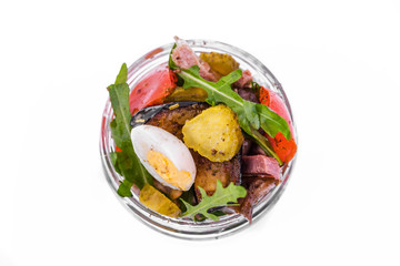 Salad with tufts of beef, eggplant and grilled tomatoes, arugula and eggs in a glass jar. The object is isolated on a white background.