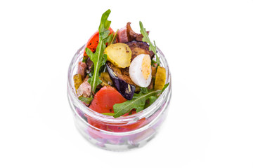 Salad with tufts of beef, eggplant and grilled tomatoes, arugula and eggs in a glass jar. The object is isolated on a white background.