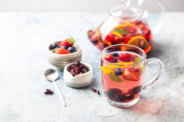 Fruit red tea with berries in glass cup on white background