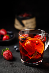 Fruit red tea with berries in glass cup on black background