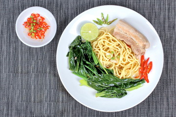 Ramen topped Chinese kale and streamed streaky pork in soup with halve green lemon and sliced chili and minced chili .
