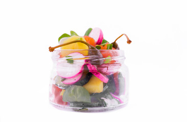 Salad with red fish, fresh vegetables - cucumber and radish, capers, egg, herbs, olives in a glass jar. The object is isolated on a white background.
