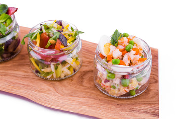 Salads in jars on a wooden tray. Trendy salad in cans. The object is isolated on a white background.