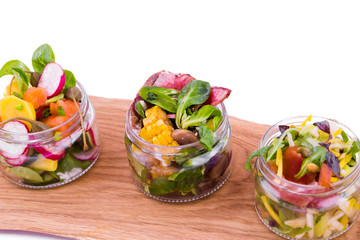 Salads in portioned jars on a wooden tray. Trendy salad in cans. The object is isolated on a white background.