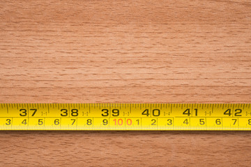 Tape measure focus on red one hundred centimeter on wooden background with copy space. Abstract business financial strategy and management concept.