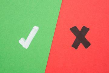 White tick symbol and black cross sign on color green red paper background. Correct or false,...