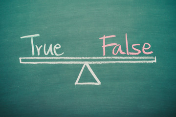 Obraz premium Text word true and false balance on seesaw drawing writing on chalkboard or blackboard background. Concept of true and false consideration in business management and investment. Real photo.