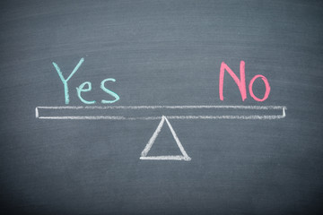 Text word Yes and No balance on seesaw drawing writing on chalkboard or blackboard background....