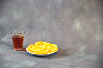 Crystal brandy glass and plate with lemon slices on a gray background.