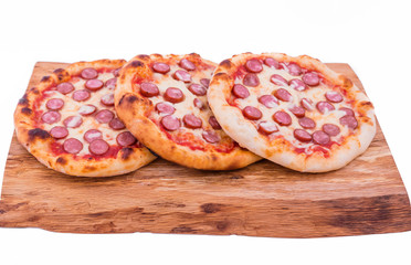 Three tasty pepperoni pizzas. Top view of hot pepperoni pizzas on a wooden tray, board, dish. The object is isolated on a white background.