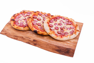 Three tasty pepperoni pizzas. Top view of hot pepperoni pizzas on a wooden tray, board, dish. The object is isolated on a white background.