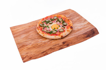 Tasty pizza with cheese, tomatoes, slices of ham and egg on a wooden dish on a white plate